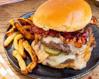 Assiette avec un smash burger double steaks au Pavé d'Isigny, bacon et cornichon, sauce de folie
